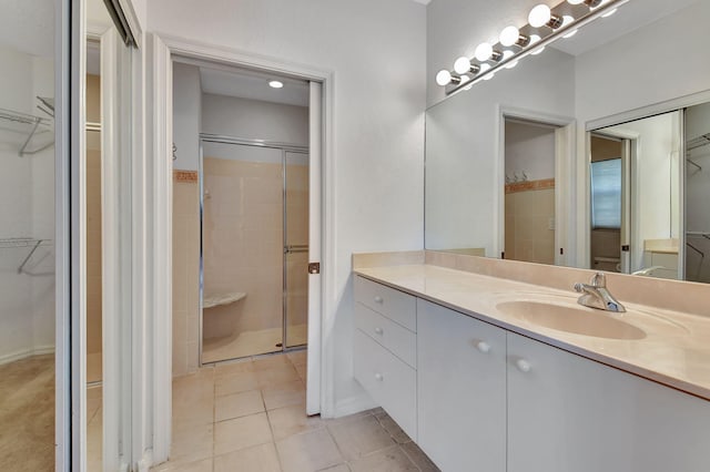 bathroom with tile patterned flooring, vanity, and a shower with door