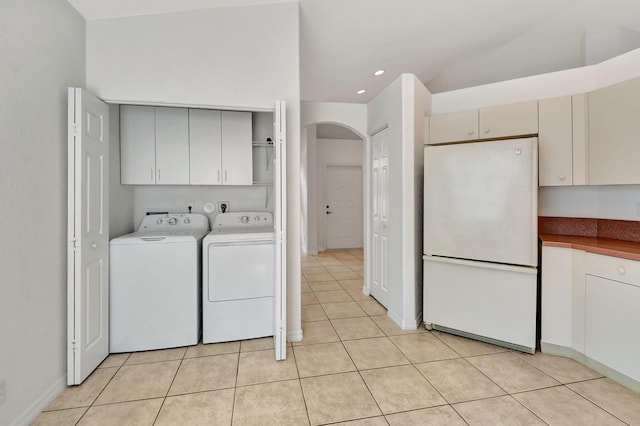 laundry area with washing machine and dryer, light tile patterned flooring, and cabinets