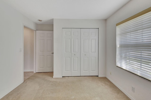 unfurnished bedroom featuring light carpet and a closet