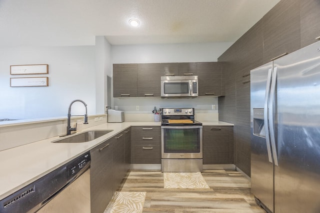 kitchen with sink, stainless steel appliances, and light hardwood / wood-style flooring