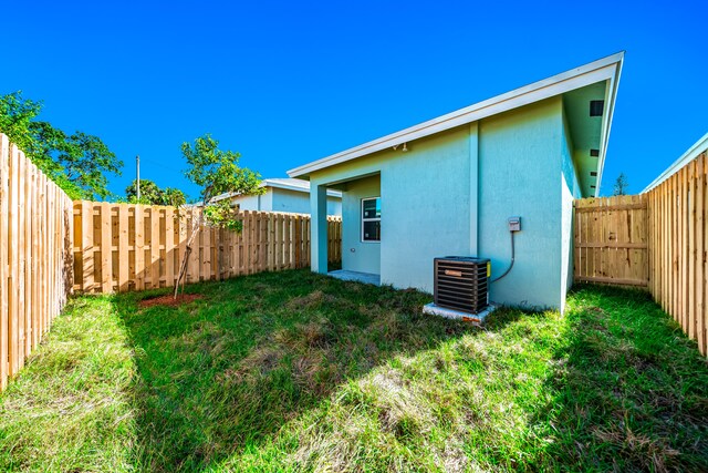 back of house with a lawn and cooling unit