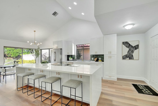 kitchen featuring white cabinetry, hanging light fixtures, light hardwood / wood-style floors, a spacious island, and appliances with stainless steel finishes