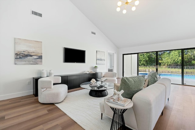 living room with an inviting chandelier, hardwood / wood-style flooring, and high vaulted ceiling