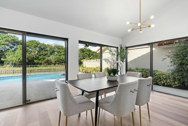 dining space featuring vaulted ceiling, a chandelier, and light hardwood / wood-style floors