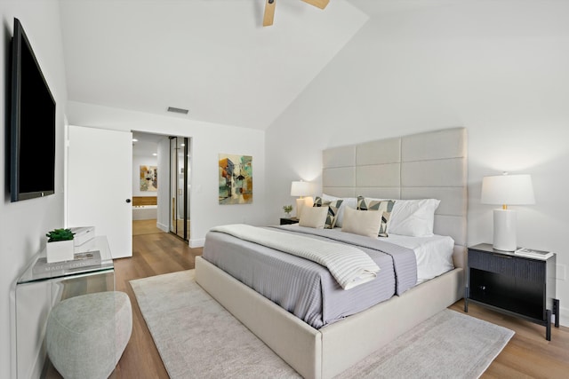 bedroom featuring vaulted ceiling, ensuite bathroom, ceiling fan, and light wood-type flooring