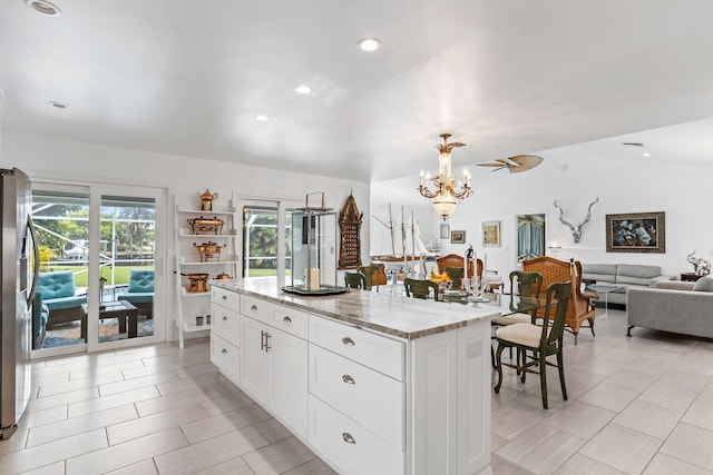 kitchen featuring a center island, white cabinetry, lofted ceiling, and light stone counters