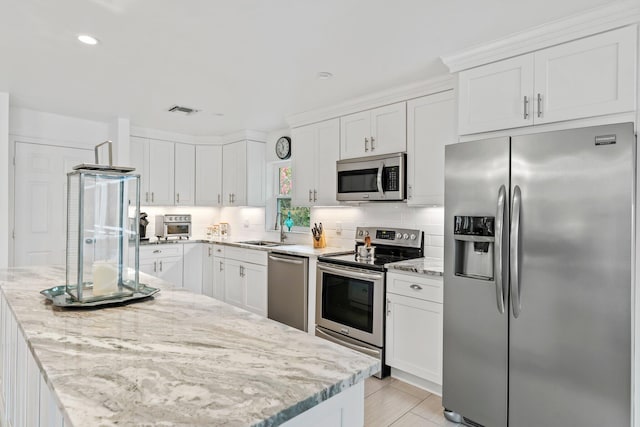 kitchen featuring sink, light stone counters, white cabinetry, and stainless steel appliances