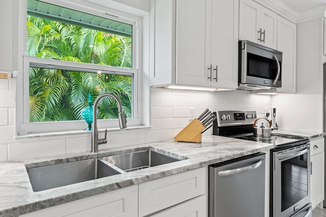 kitchen featuring light stone countertops, sink, stainless steel appliances, tasteful backsplash, and white cabinets