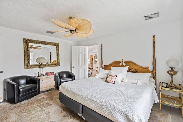 bedroom featuring ceiling fan, wood-type flooring, and a textured ceiling