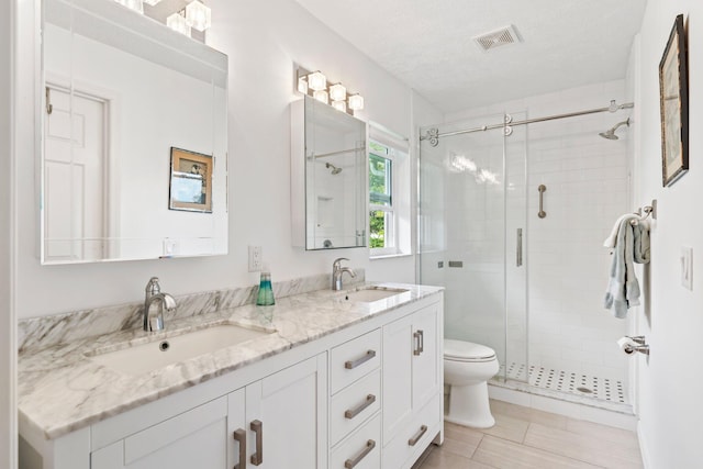 bathroom featuring vanity, toilet, a shower with shower door, and a textured ceiling