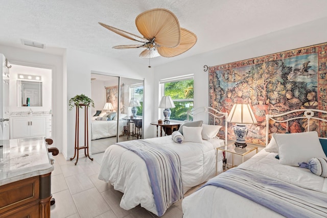 bedroom featuring a textured ceiling, ceiling fan, sink, connected bathroom, and a closet