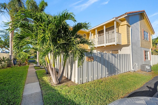 view of home's exterior with central AC unit, a yard, and a balcony