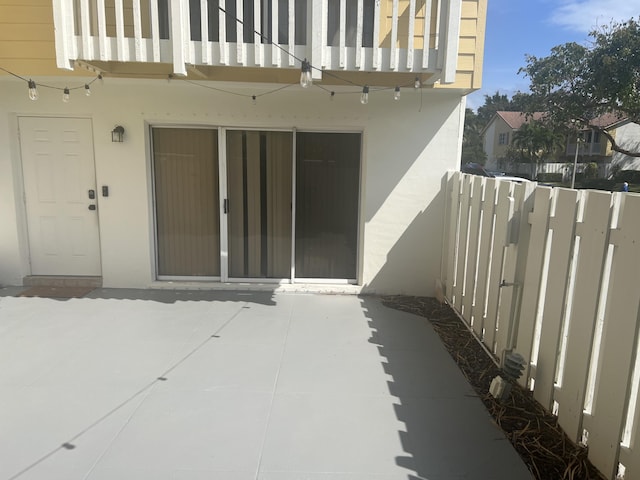 view of exterior entry featuring a patio and a balcony