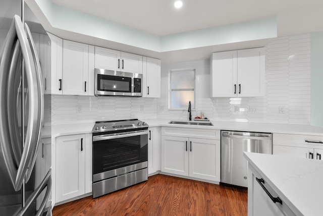 kitchen featuring sink, appliances with stainless steel finishes, white cabinetry, dark hardwood / wood-style floors, and tasteful backsplash