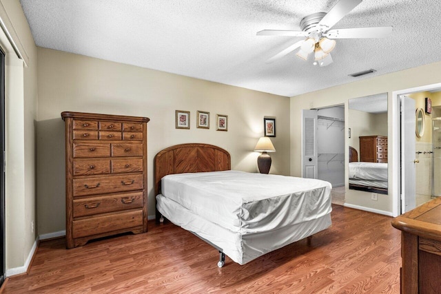 bedroom with ensuite bathroom, ceiling fan, a textured ceiling, and hardwood / wood-style flooring