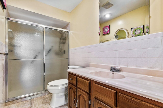 bathroom with vanity, a shower with shower door, tile walls, and toilet