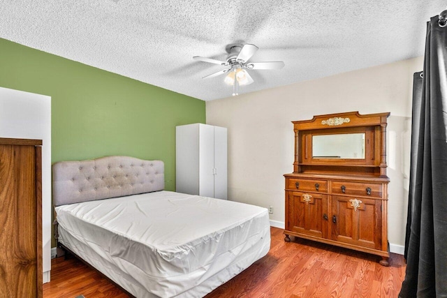 bedroom with a textured ceiling, light hardwood / wood-style floors, and ceiling fan