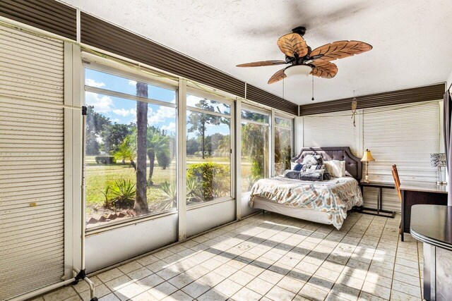 bedroom featuring ceiling fan, light tile patterned floors, and a textured ceiling