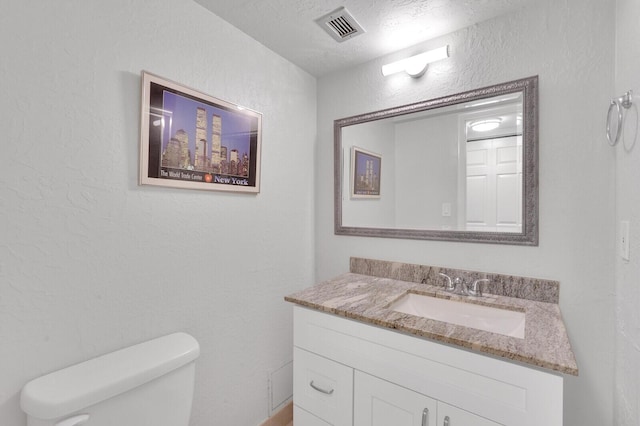 bathroom featuring a textured ceiling, vanity, and toilet