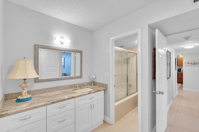 bathroom with tile patterned flooring, vanity, combined bath / shower with glass door, and a textured ceiling