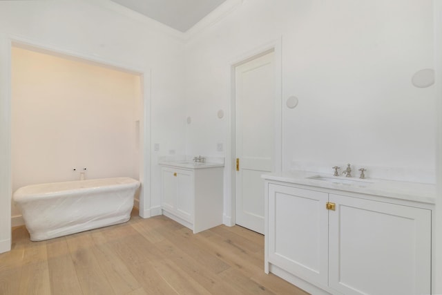 234 Miramar Way, West Palm Beach, FL 33405 - bathroom featuring wood finished floors, two vanities, a freestanding tub, and ornamental molding