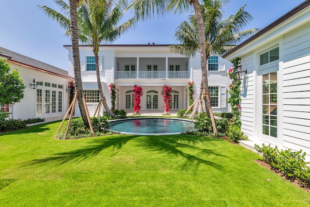 234 Miramar Way, West Palm Beach, FL 33405 - back of house with french doors, a lawn, an outdoor pool, and a balcony