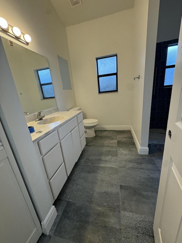 bathroom featuring a tile shower, tile patterned flooring, vanity, and toilet