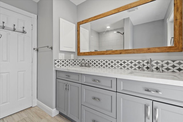 bathroom with tasteful backsplash, hardwood / wood-style floors, vanity, and a tile shower