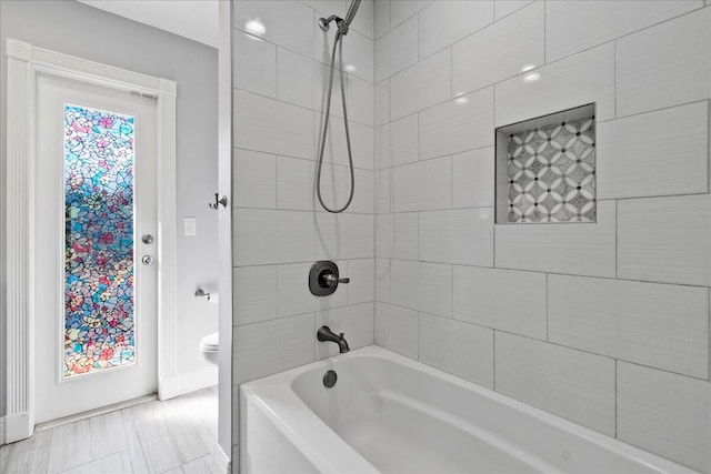 bathroom with toilet and tiled shower / bath