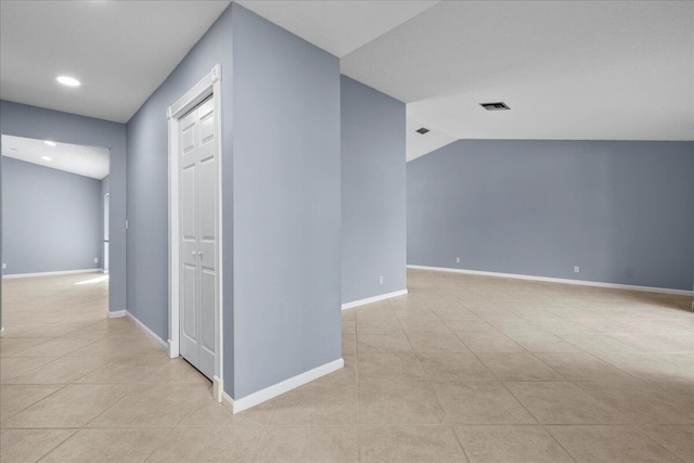 corridor with light tile patterned floors and lofted ceiling