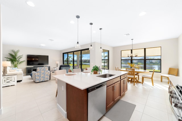 kitchen with sink, hanging light fixtures, stainless steel appliances, an inviting chandelier, and a kitchen island with sink