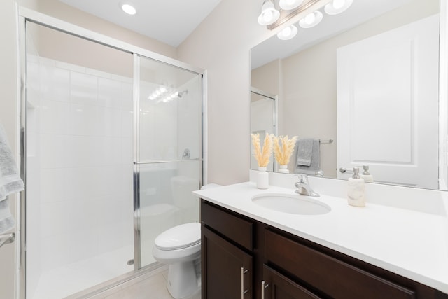 bathroom featuring tile patterned flooring, vanity, a shower with shower door, and toilet