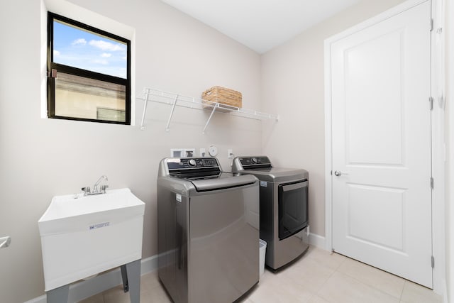 laundry area featuring washer and clothes dryer, light tile patterned floors, and sink