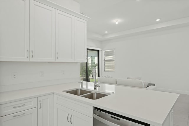 kitchen featuring kitchen peninsula, white cabinetry, stainless steel dishwasher, and sink