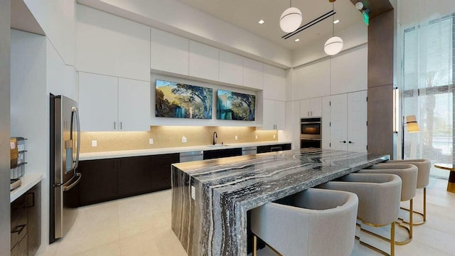 kitchen with dark stone countertops, white cabinets, a kitchen island, and appliances with stainless steel finishes