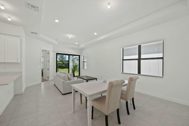 tiled dining space with a tray ceiling