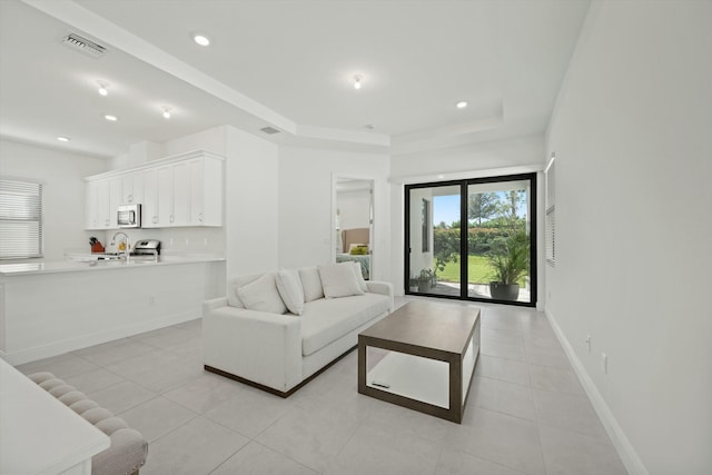 living room with light tile patterned flooring and a tray ceiling