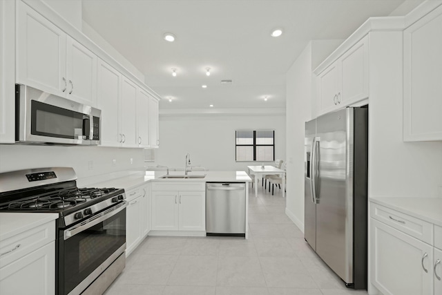 kitchen with kitchen peninsula, sink, light tile patterned floors, appliances with stainless steel finishes, and white cabinetry