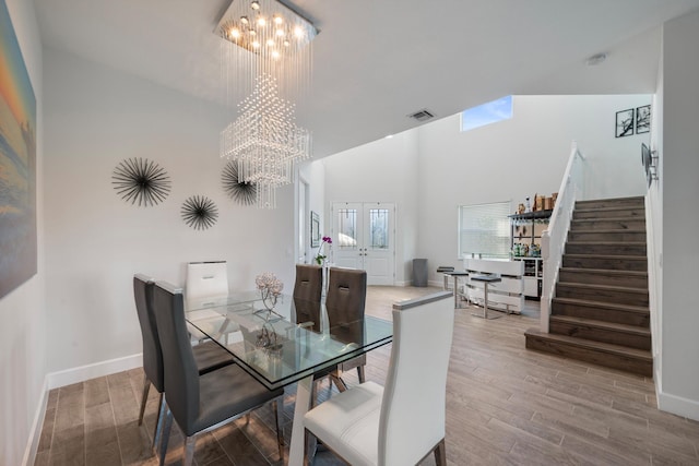 dining room featuring french doors, an inviting chandelier, high vaulted ceiling, and hardwood / wood-style flooring