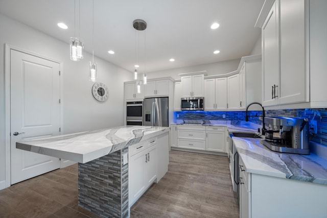 kitchen with white cabinets, a kitchen island, hanging light fixtures, and appliances with stainless steel finishes