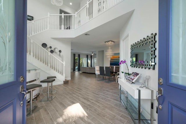 entryway featuring a towering ceiling, a chandelier, and hardwood / wood-style flooring