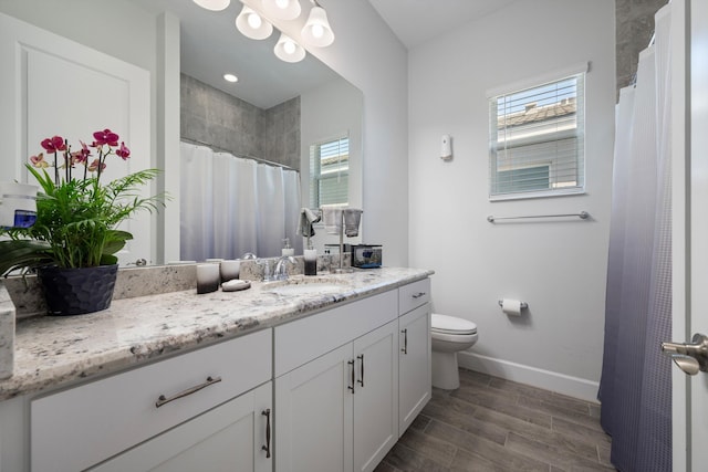 bathroom featuring hardwood / wood-style flooring, plenty of natural light, toilet, and vanity