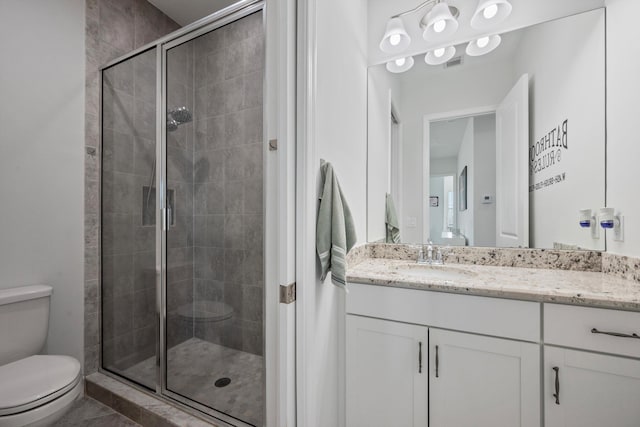 bathroom featuring a shower with door, vanity, and toilet