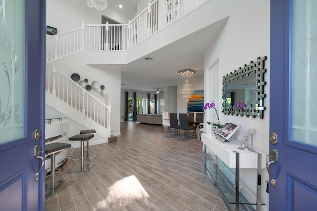 entrance foyer with a towering ceiling, ceiling fan with notable chandelier, and hardwood / wood-style flooring