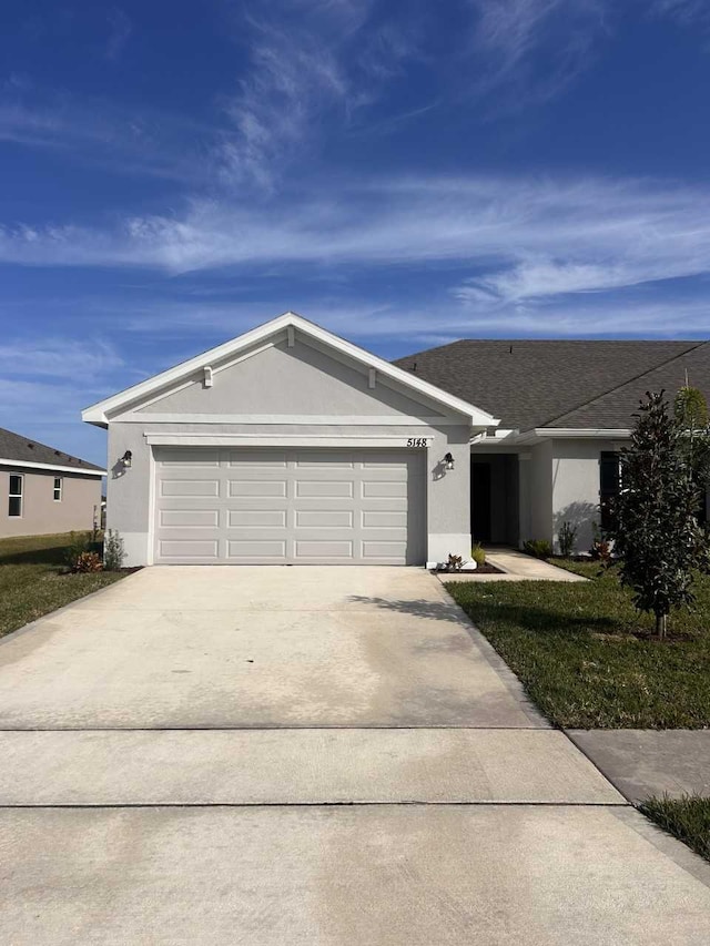 single story home featuring a garage and a front yard