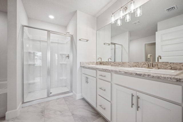 bathroom featuring a shower with door and vanity