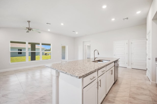 kitchen featuring white cabinetry, dishwasher, light stone countertops, sink, and an island with sink