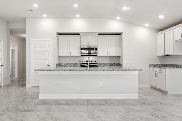 kitchen with appliances with stainless steel finishes, white cabinetry, a kitchen island with sink, and lofted ceiling