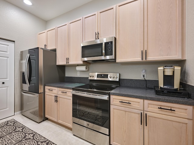 kitchen with light brown cabinets, light tile patterned floors, and appliances with stainless steel finishes