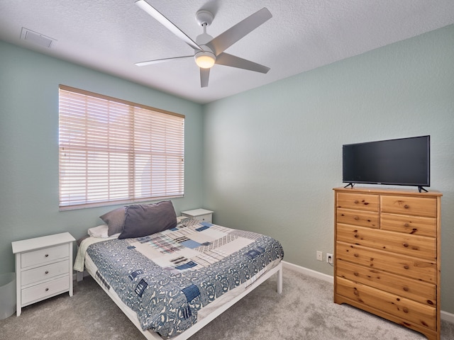 bedroom with ceiling fan, carpet floors, and a textured ceiling